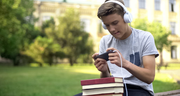 boy procrastinating by listening to music holding books
