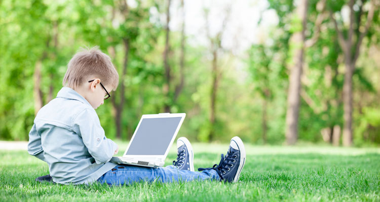 Little boy using computer outside