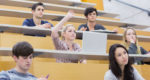 students hand raised in college lecture hall