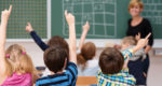 children raising hands in school