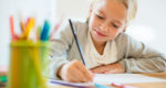 Child writing with pencil at desk