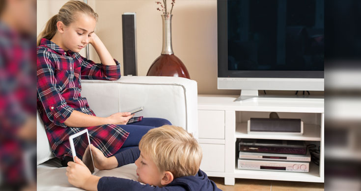 siblings using phone and tablet in livingroom