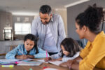 Two parents help their children with homework.