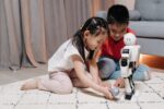 Robotics for kids. Two children sit on the ground and play with a robot together.