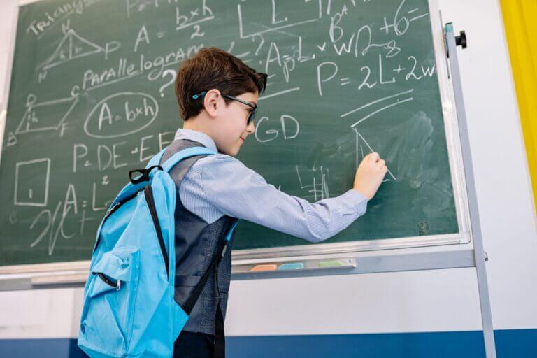 A student works on equations on a chalkboard.