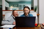 Mother and son working together with their laptop at home