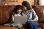 Mother and daughter working together with their laptop at home